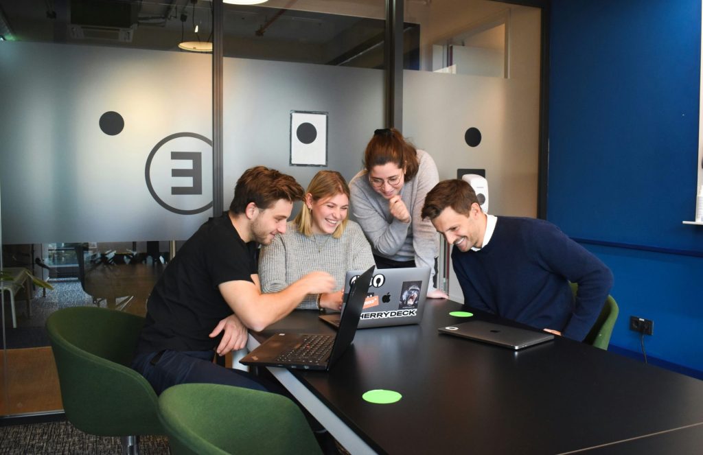 team crowded around a laptop smiling
