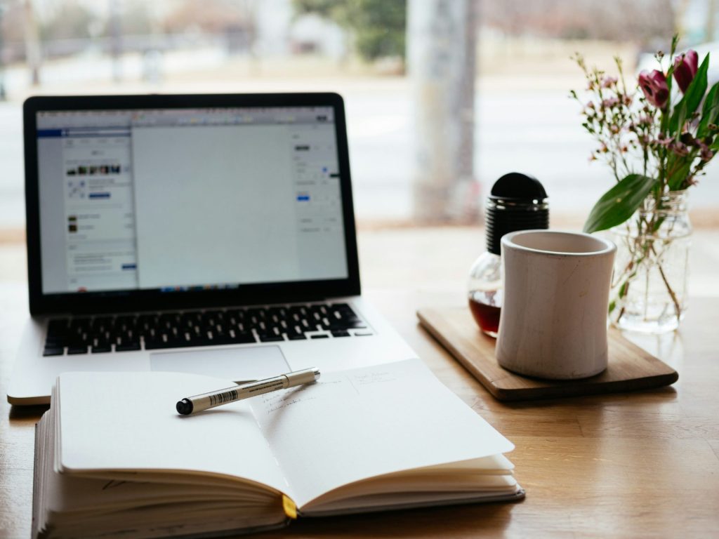 Notebook on a desk infront of laptop