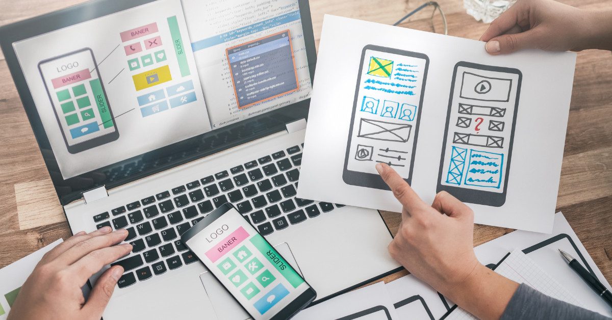 Two people looking at website wireframes on paper and pc